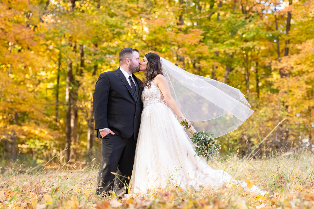 bride and groom kissing in the fall