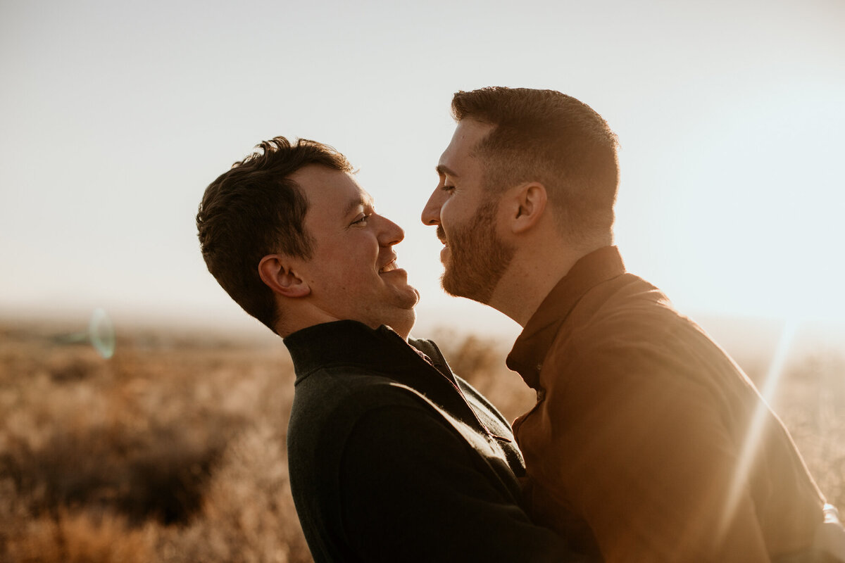 man leaning into same sex fiancé to kiss him