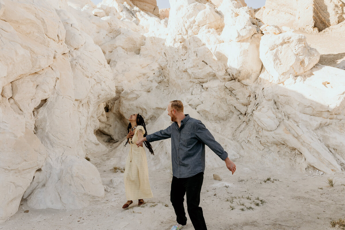 man and woman playfully walking around a white rock in New Mexico