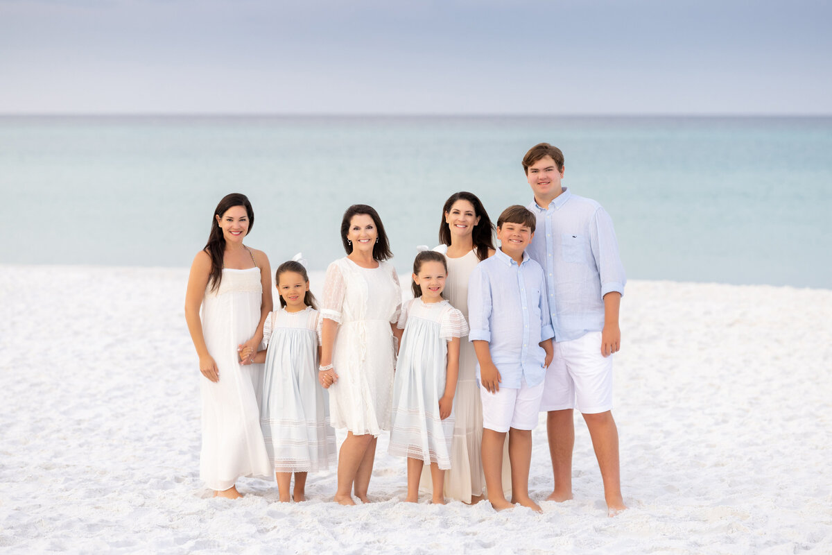 A family in light colored clothes standing at the beach during sunrise in Grayton Beach Florida
