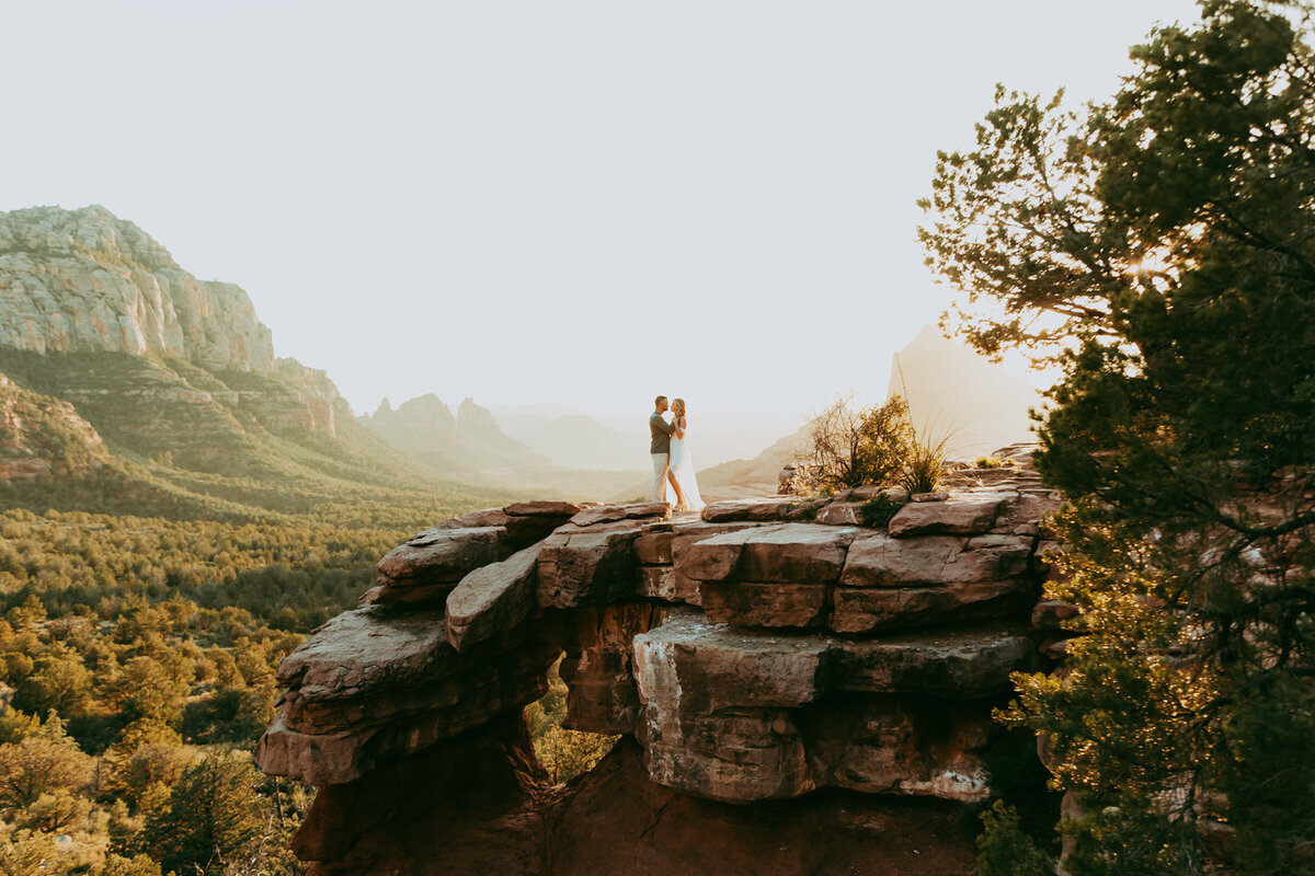 man and woman stand on a cliff edge in sedona