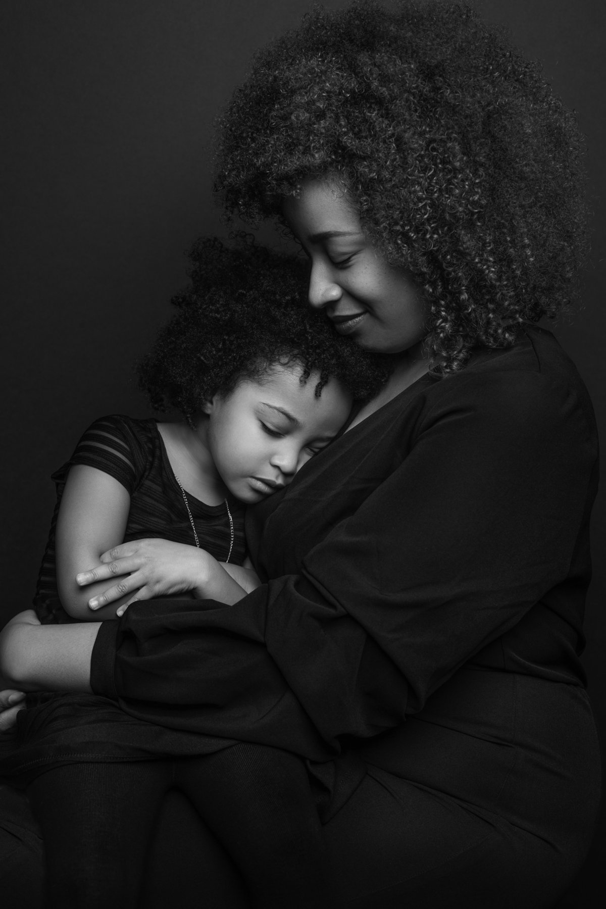 A mother and her young daughter share a tender moment as they pose for a black and white portrait at Janel Lee Photography in Cincinnati Ohio