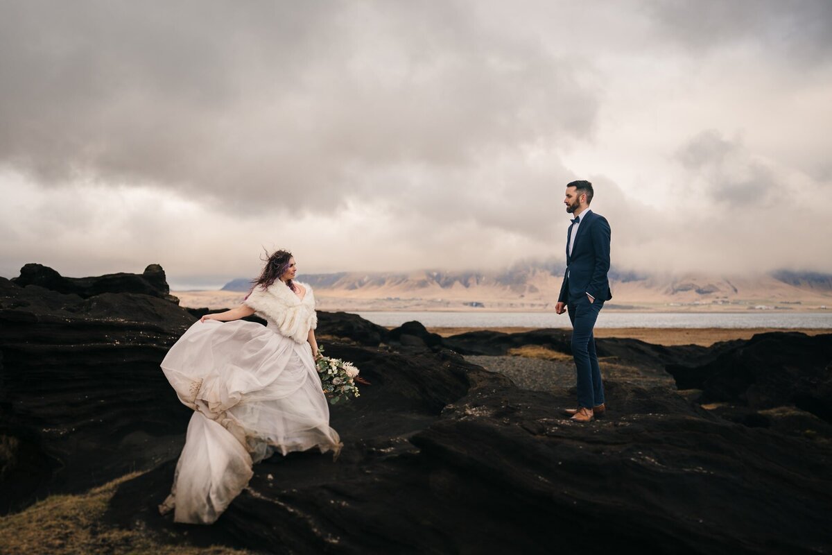 In a dramatic portrait, this couple stands tall and strong on jagged rocks, symbolizing the enduring strength of their love amidst the challenges and beauty of their journey together.