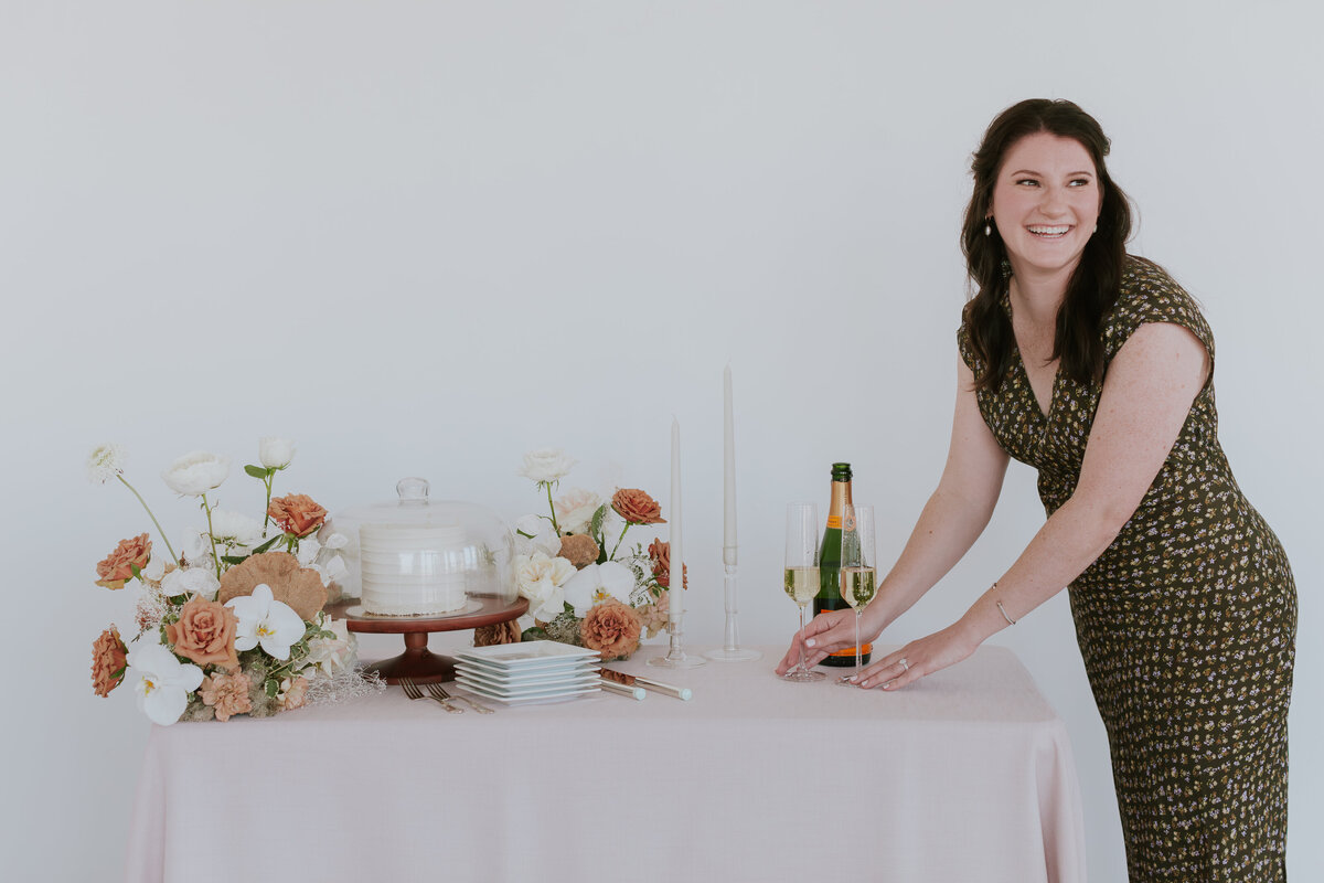 event-planner-placing-charmpagne-on-cake-table-for-brand-session-the-frame-charlotte