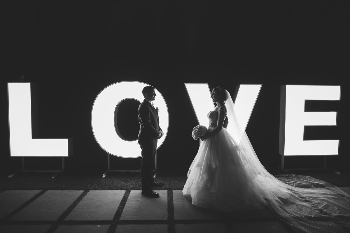 bride and groom in front of the love sign at Prime