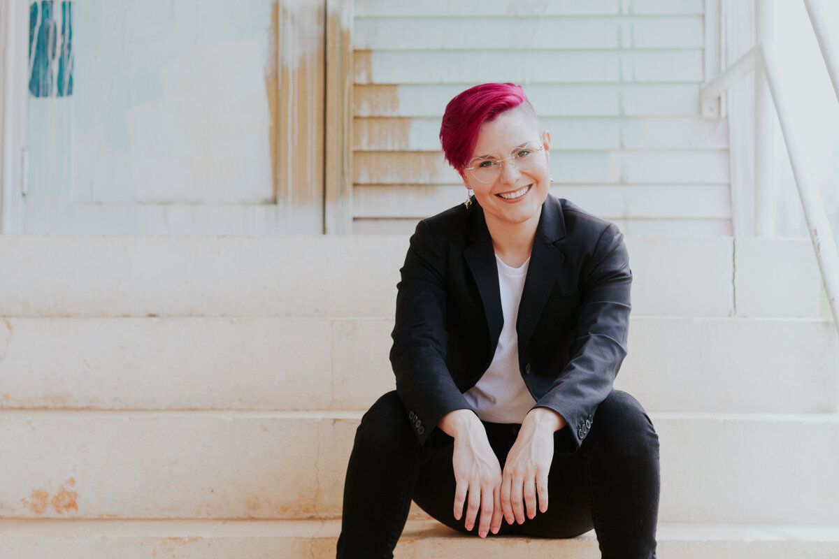 female-web-designer-black-suit-seated-headshot-colorful-background-for-brand-session-camp-north-end-charlotte