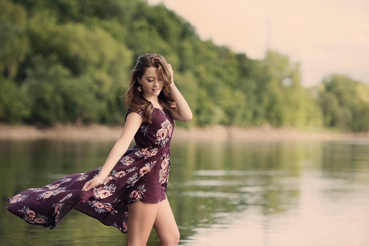 girl on side of river with flowing patterned floral dress