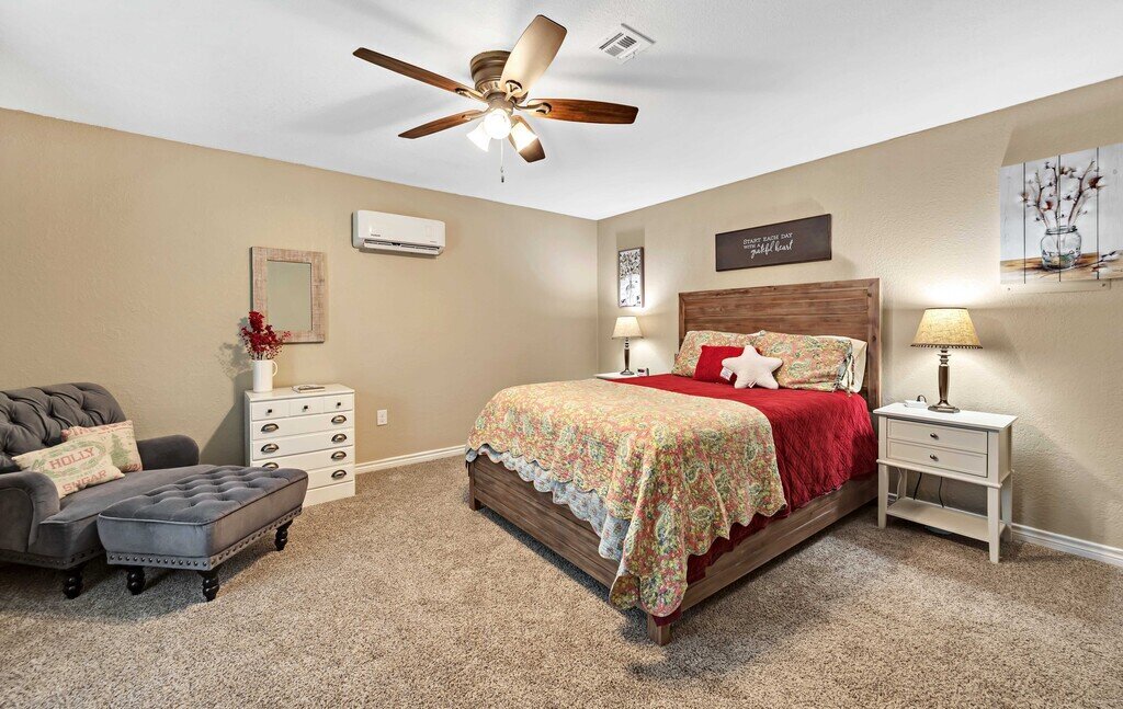 Bedroom with comfortable bedding and additional seating in this four-bedroom, four-bathroom vacation rental home and guest house with free WiFi, fully equipped kitchen, firepit and room for 10 in Waco, TX.