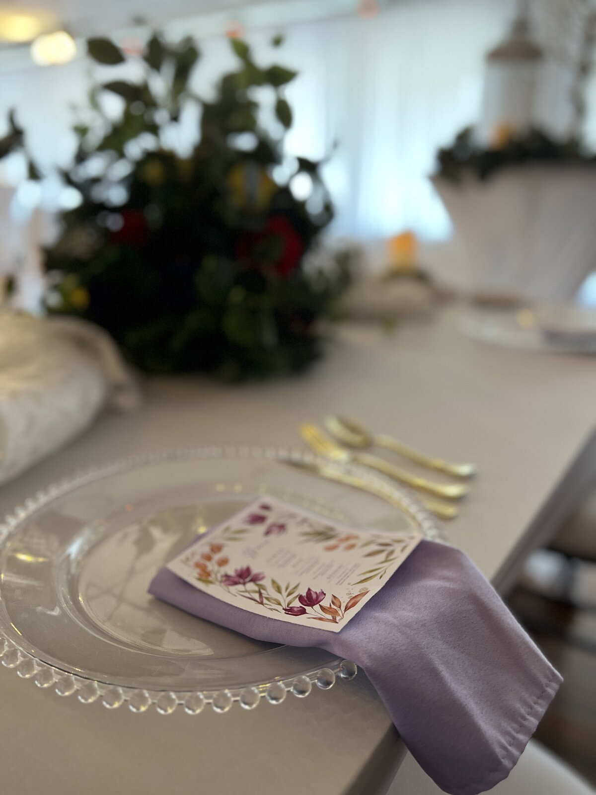 Wedding reception dinner plate and menu in our Clearwater event venue inclusive decor packages - Featuring classic clear charger plates and whimsical flowers for an enchanting dining experience