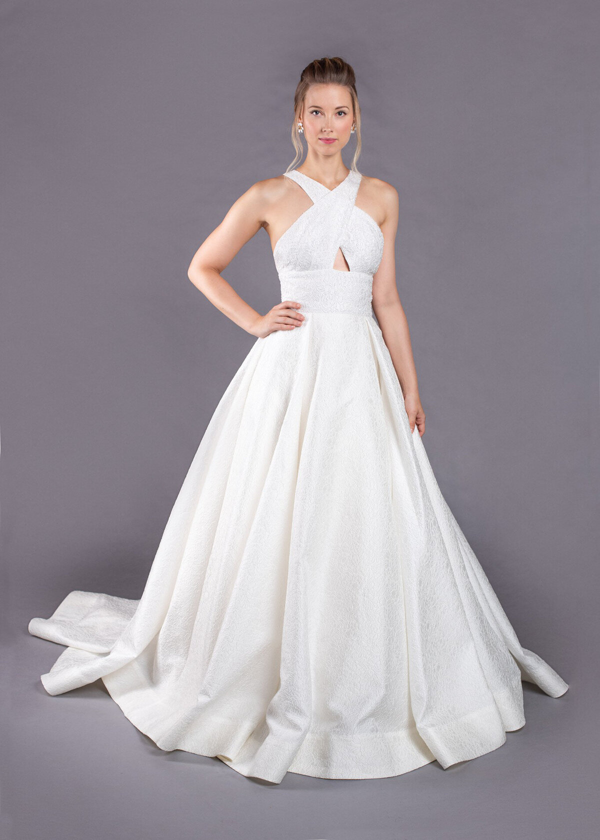 The Joan style is a timeless but modern ballgown wedding dress in a textured floral fabric and cross-over neckline.\