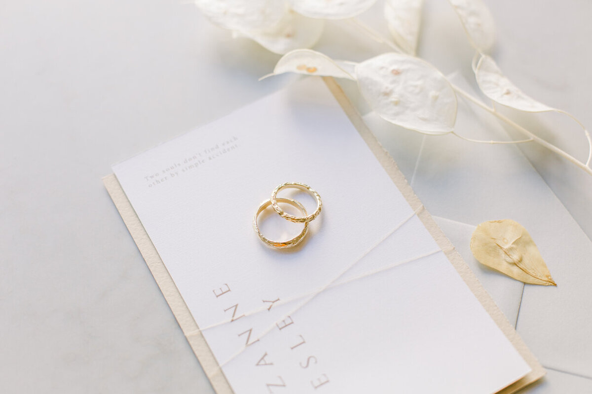 Closeup of elegant, timeless wedding stationery with gold wedding bands for him and her for an intimate wedding photoshoot at the Tassenmuseum organized by Lovely & Planned