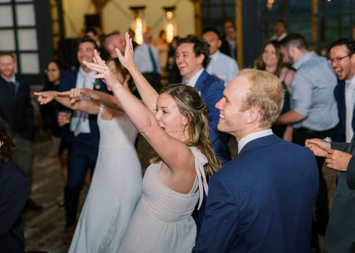 The bridal party and other friends dance to the music during an outdoor summer wedding