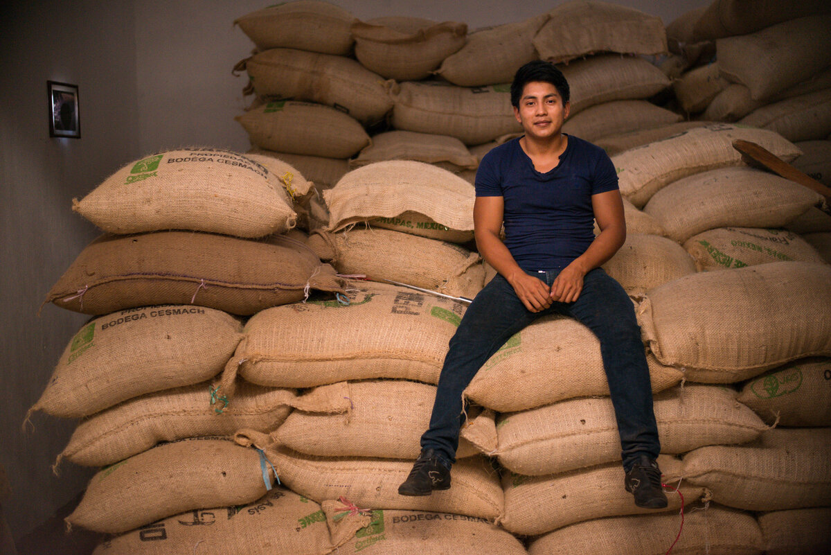 Man sits on burlap coffee bags for Food 4 Farmers  non profit