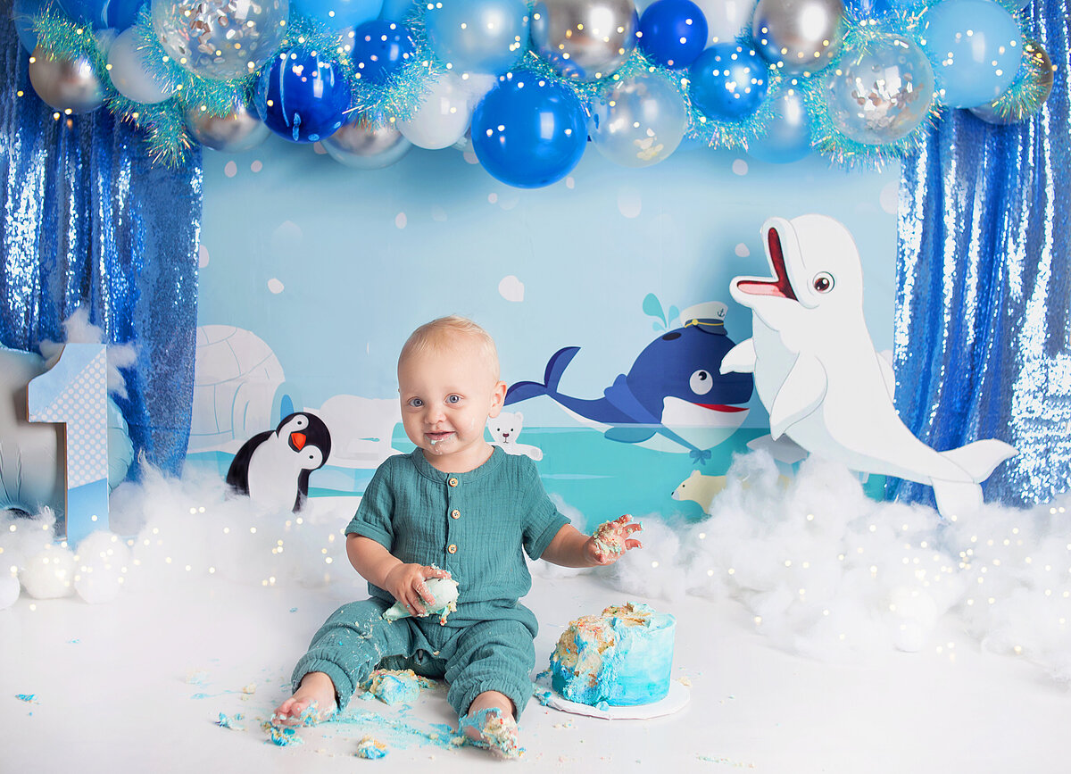 Little boy eating cake wearing blue romper during cake smash photoshoot in Brentwood Tennessee photography studio