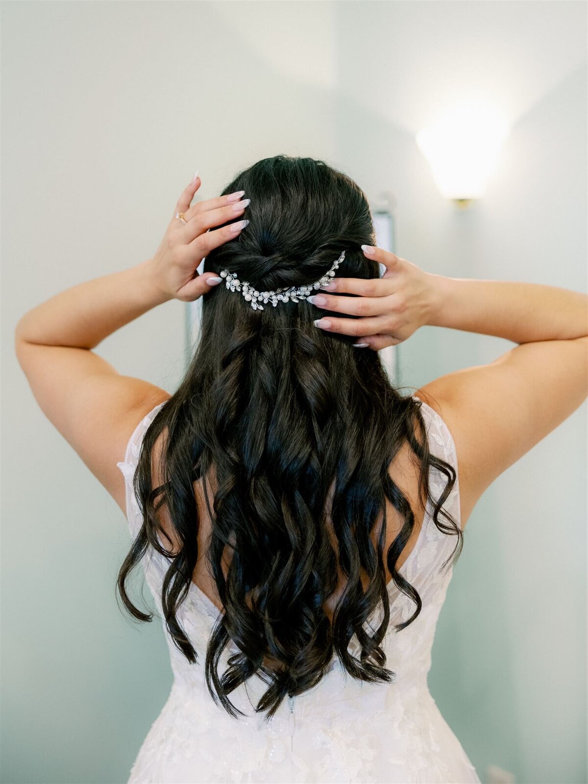 The back of a woman with flowing black hair and tiara.