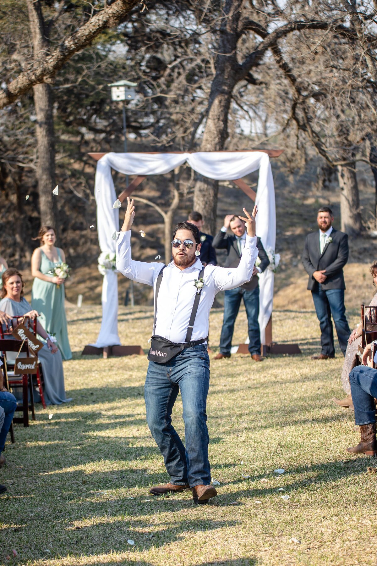 flower man tosses petals into the air down aisle at Boerne Texas wedding