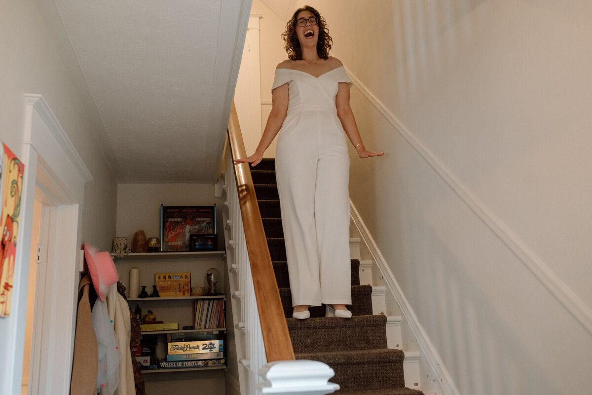 bride comes down the stairs in her bridal romper