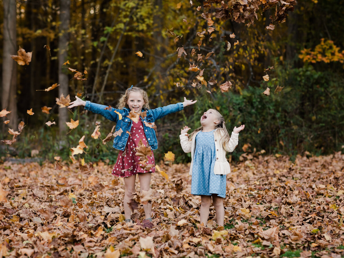sisters playing in the leaves for family photos