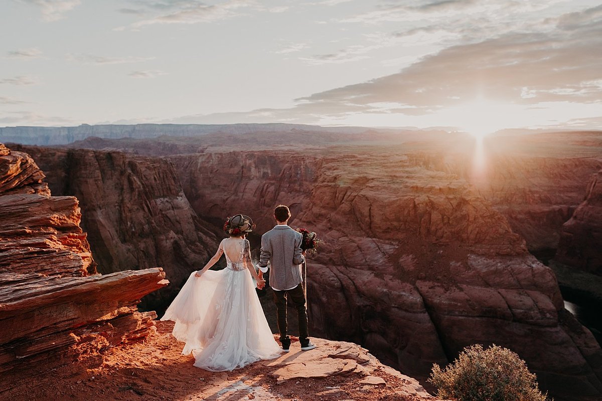 couple stand on the edge of a cliff looking at a river