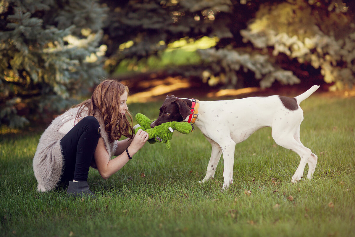 Backyard session, and this tween girl is face-to-face with her dog, both holding on to a dog toy.