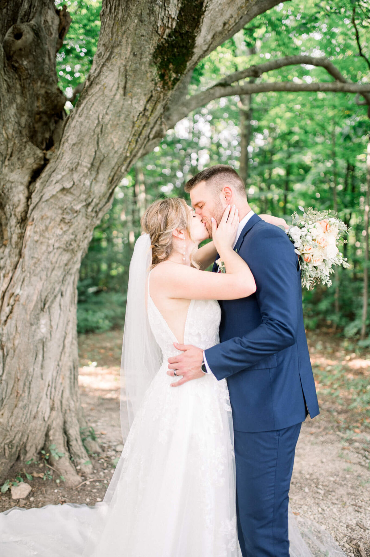 Bride and groom kissing under large tree  captured by Niagara wedding photographer