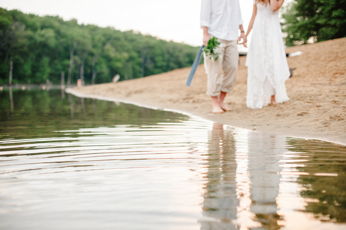 couple walks hand in hand over sand shore casual wedding photography and chester woods regional park rochester minnesota