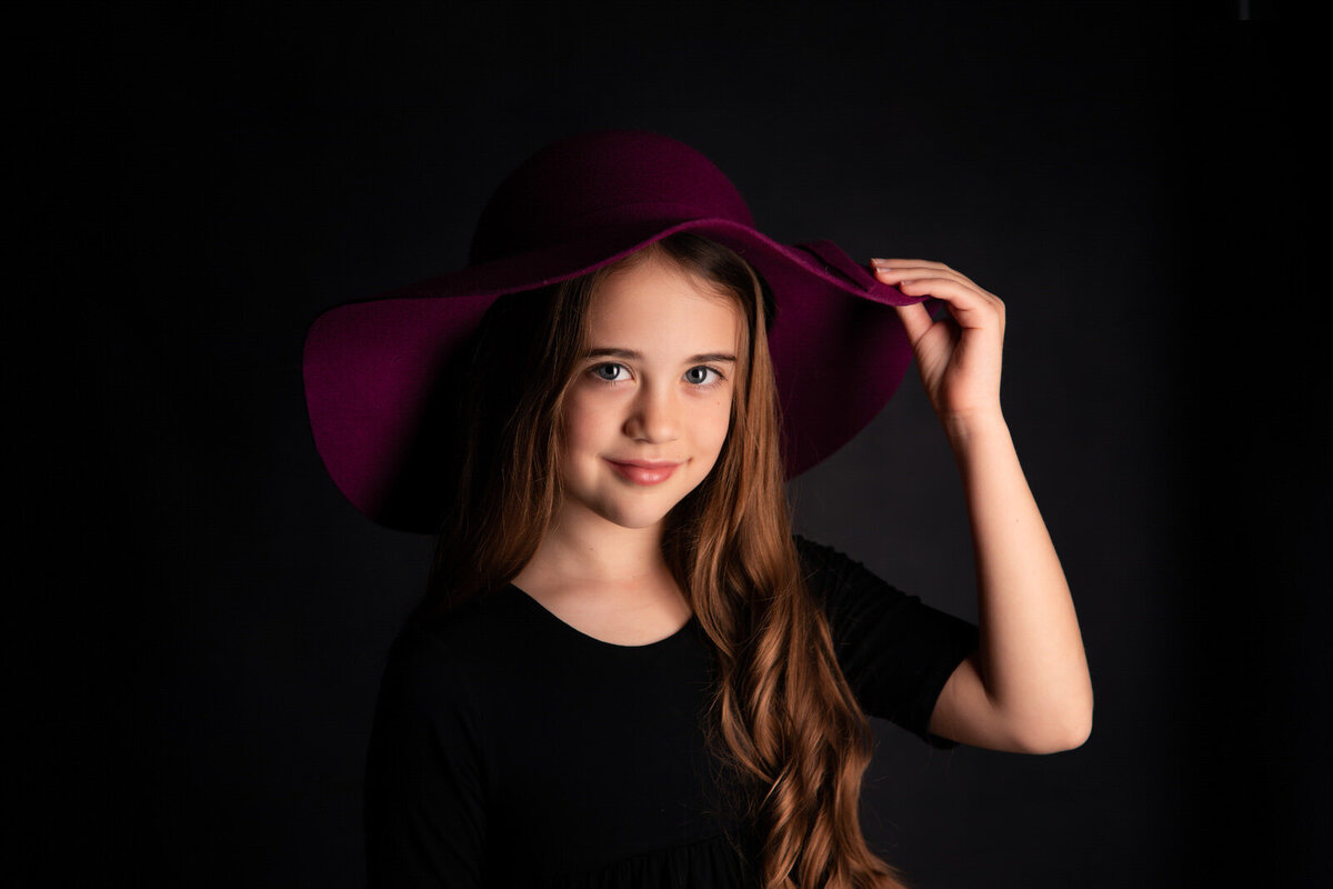 tween-girl-holding-pink-hat-in-studio