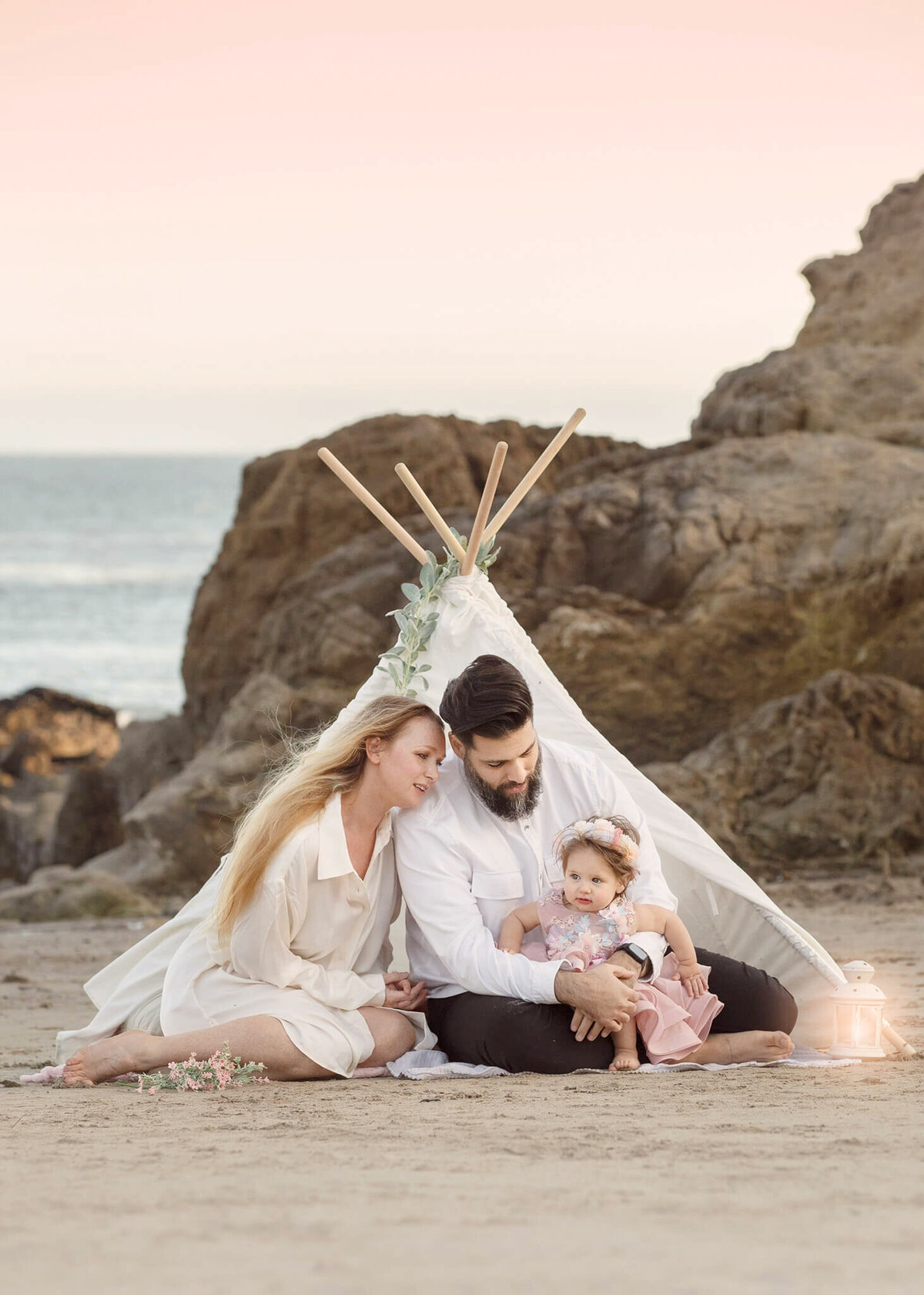 Mom and dad with their toddler daughter photographed in Malibu while sitting in a tent