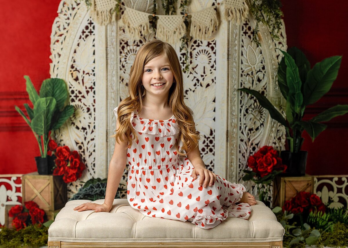 Girl sitting on a bench smiling in a with and dress dress for valentines