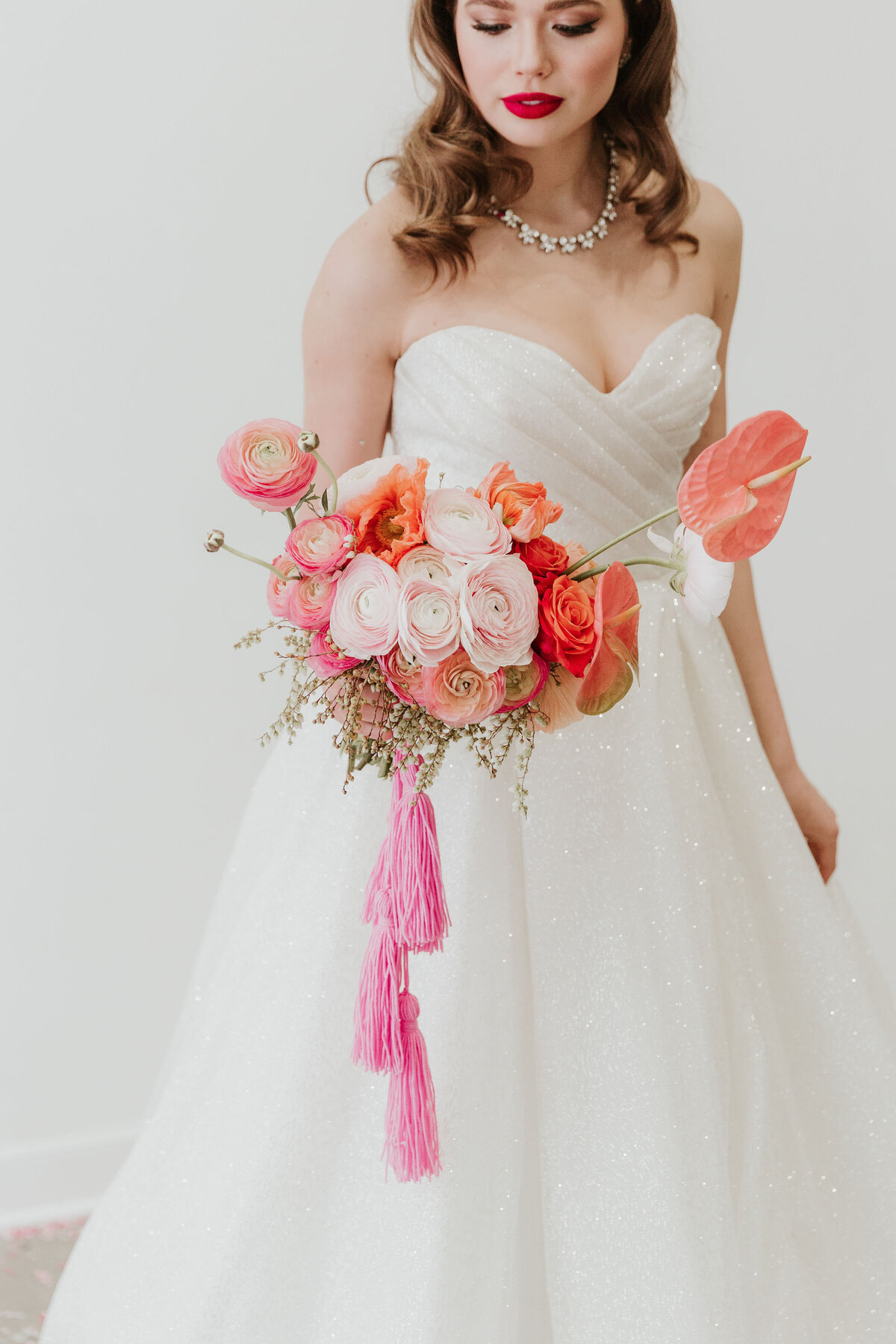 Contemporary bride holding colourful pink bouquet, wearing gown from Cameo & Cufflinks, a contemporary bridal boutique based in Calgary, Alberta. Featured on the Brontë Bride Vendor Guide.