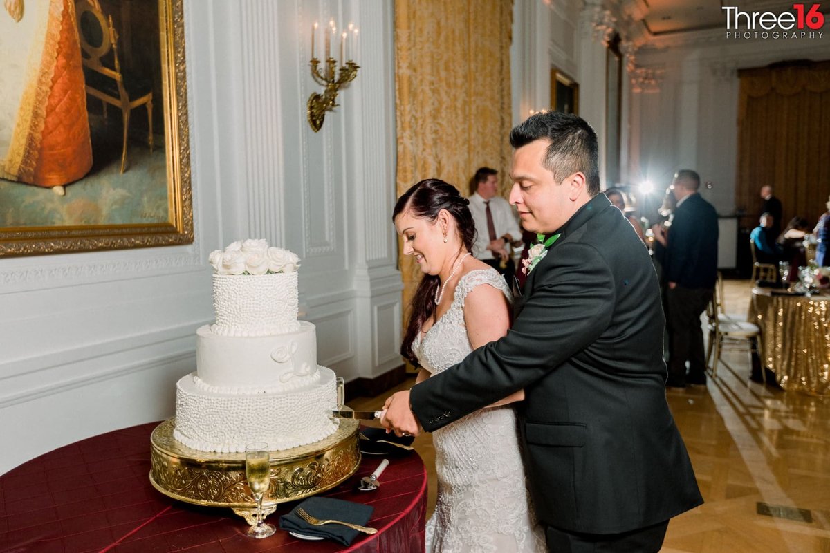 Bride and Groom cut into 3-tiered white wedding cake