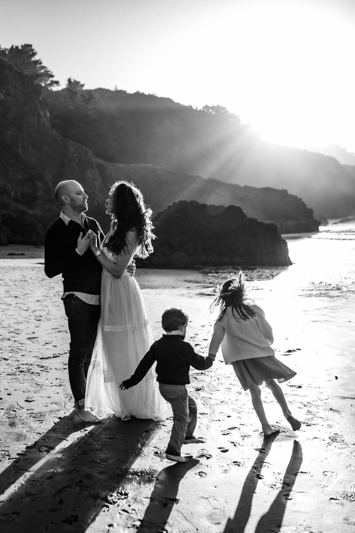 Bay Area family portrait on beach of parents embraced and children running