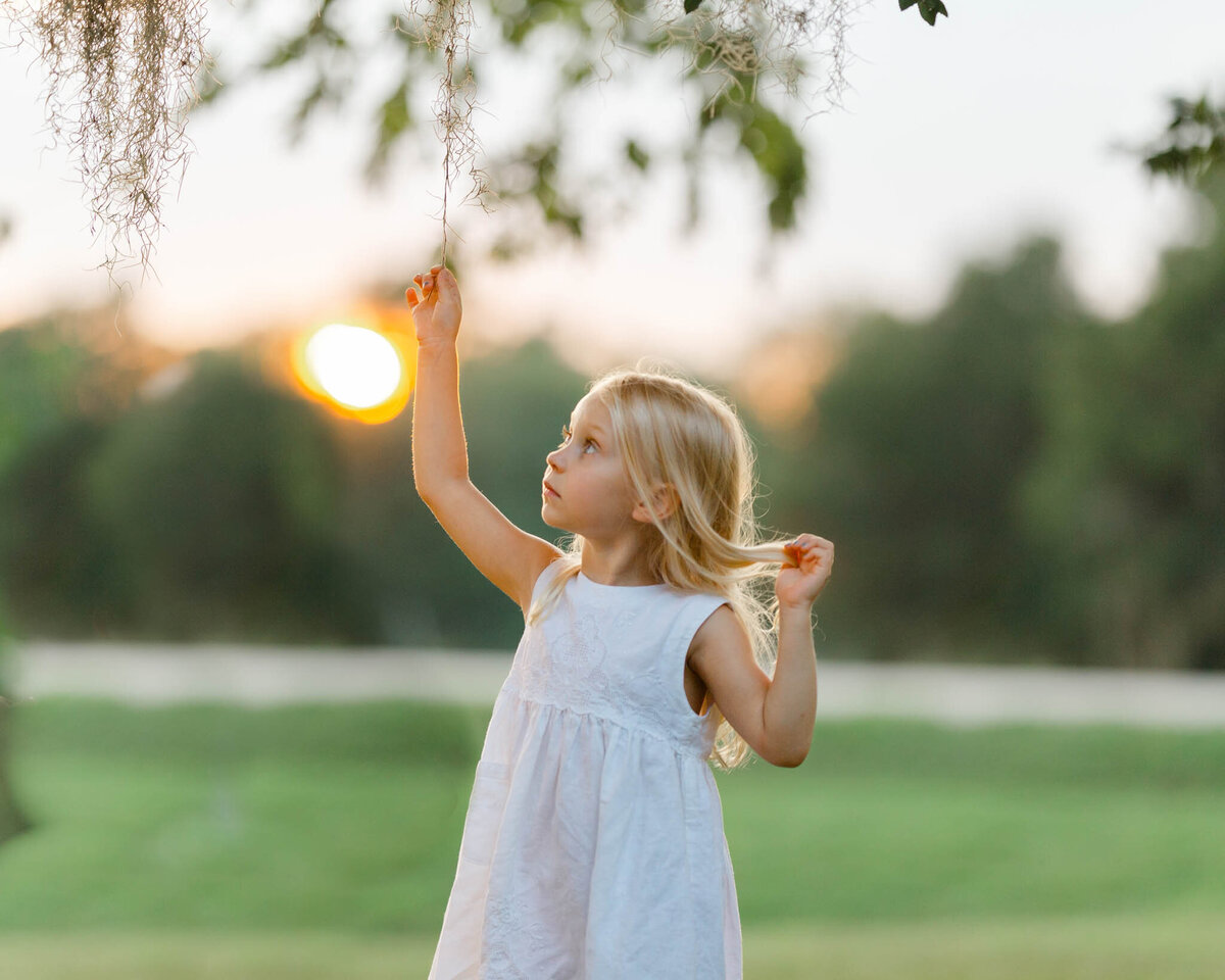 girl holding tree during sunset