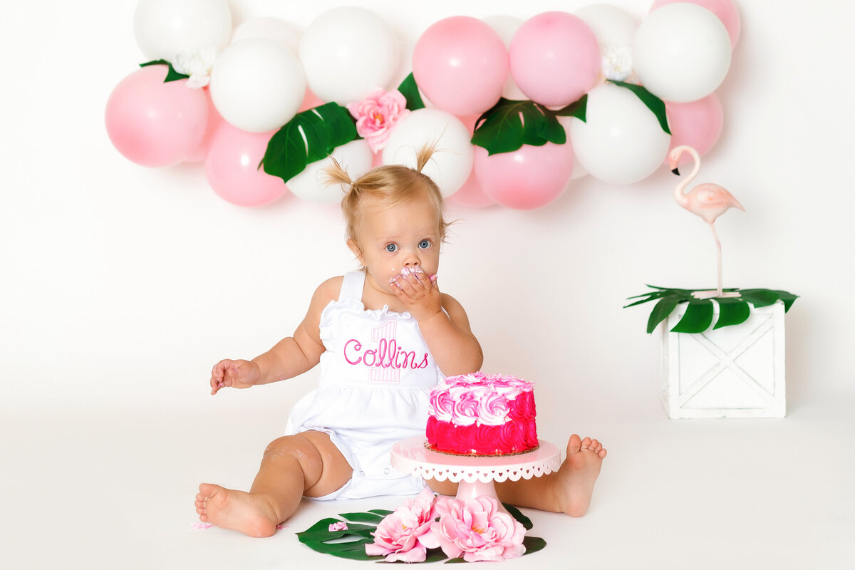 Cake Smash Photographer, a baby girl eats cake before balloons and Monstera leaves