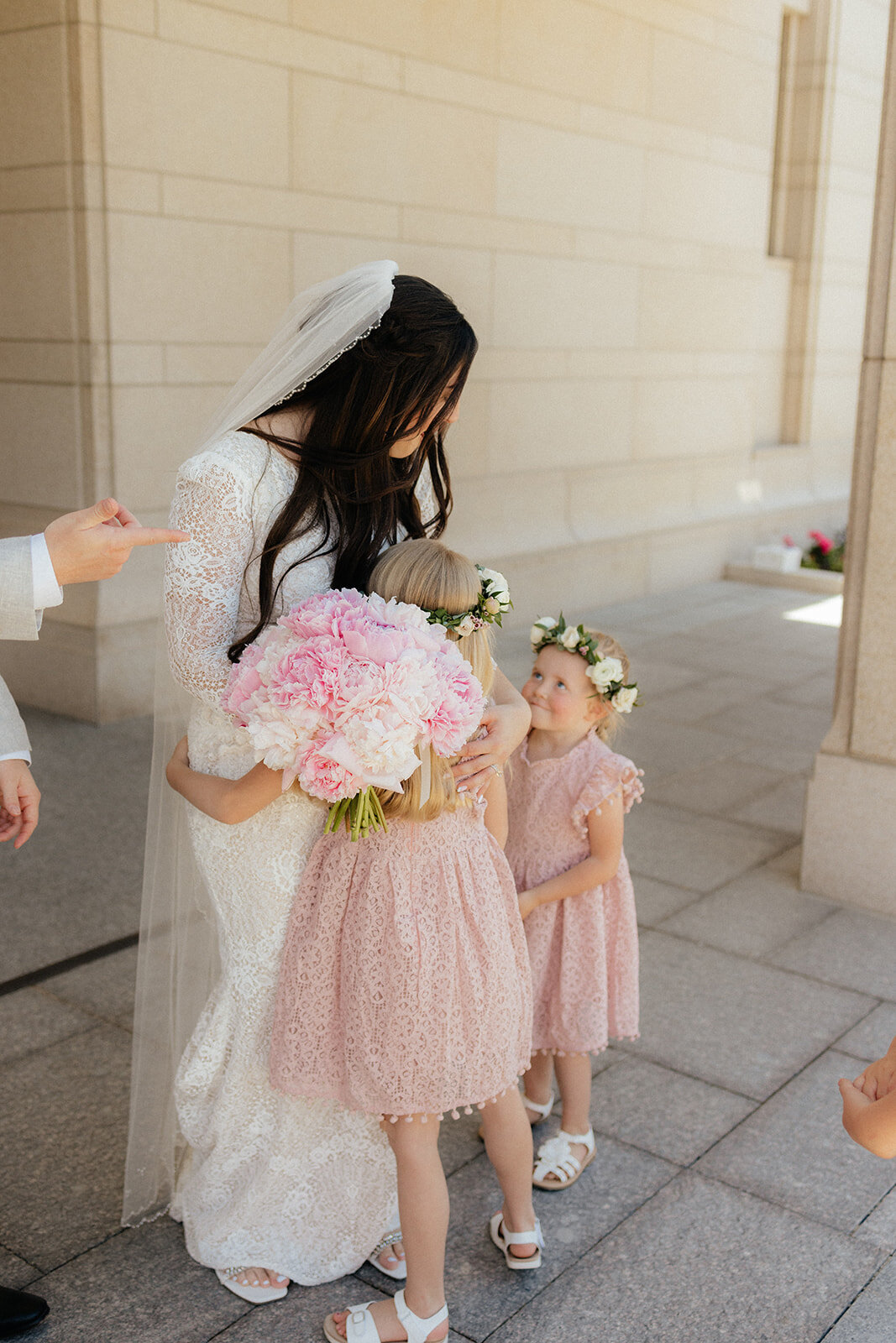 Bride with peony bouquet and flower girls with flower crowns.