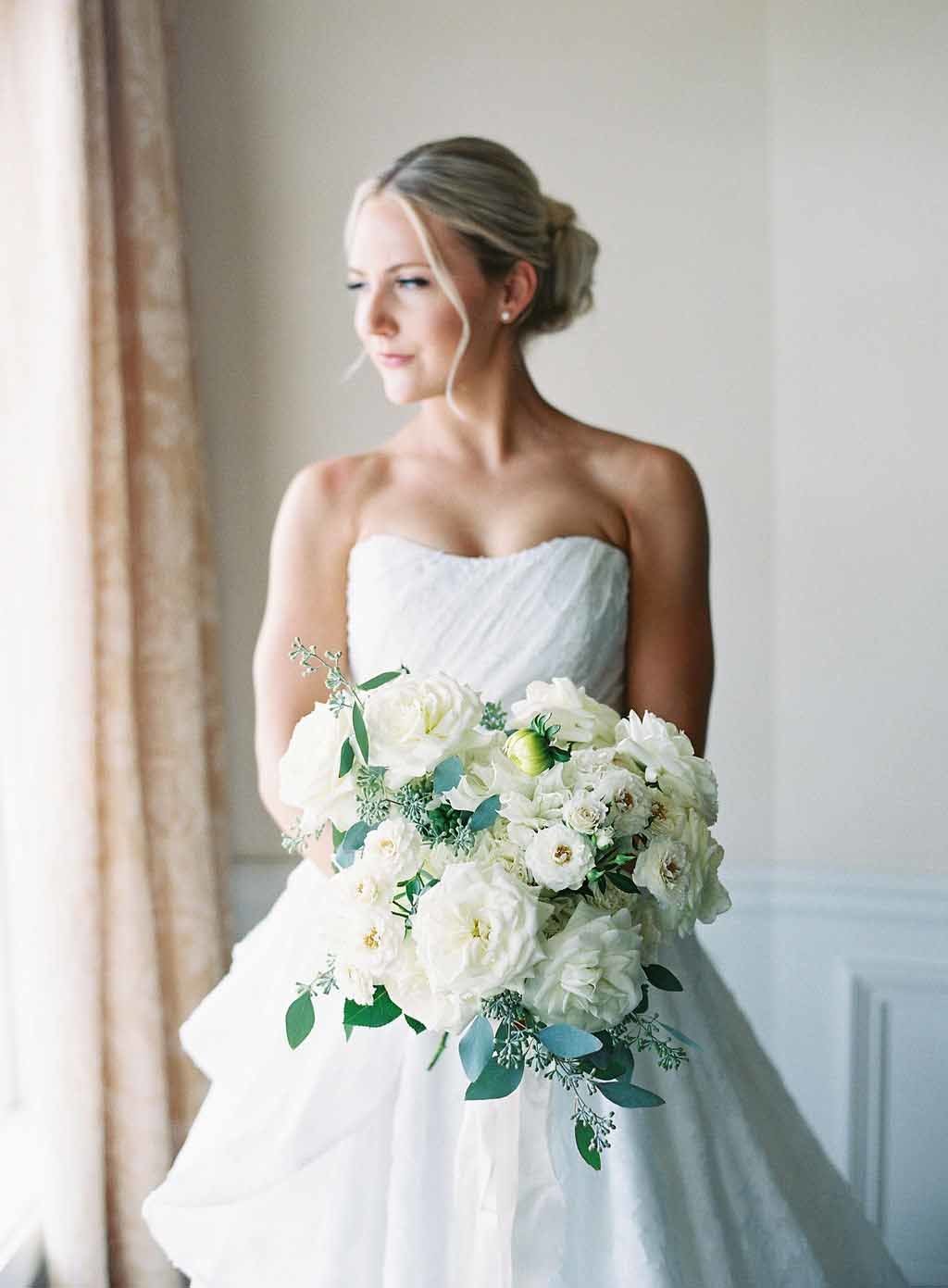 bride in white dress holding bouquet of white garden flowers