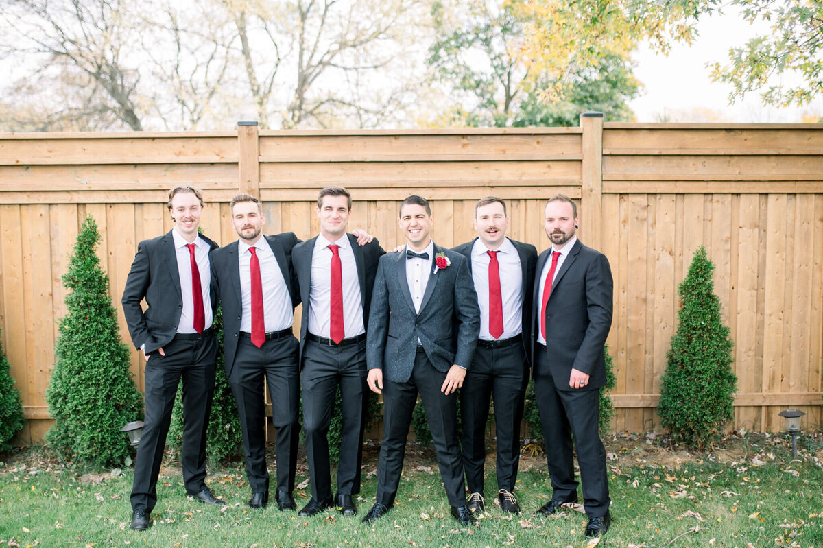 All groomsmen standing in a line with the groom in the middle. Captured by Niagara wedding photographer