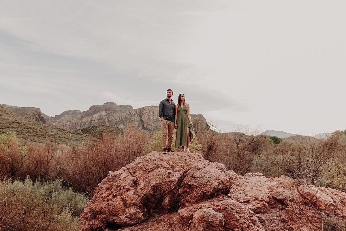 Couple stand on large red rocks in Phoenix desert for their engagement photos