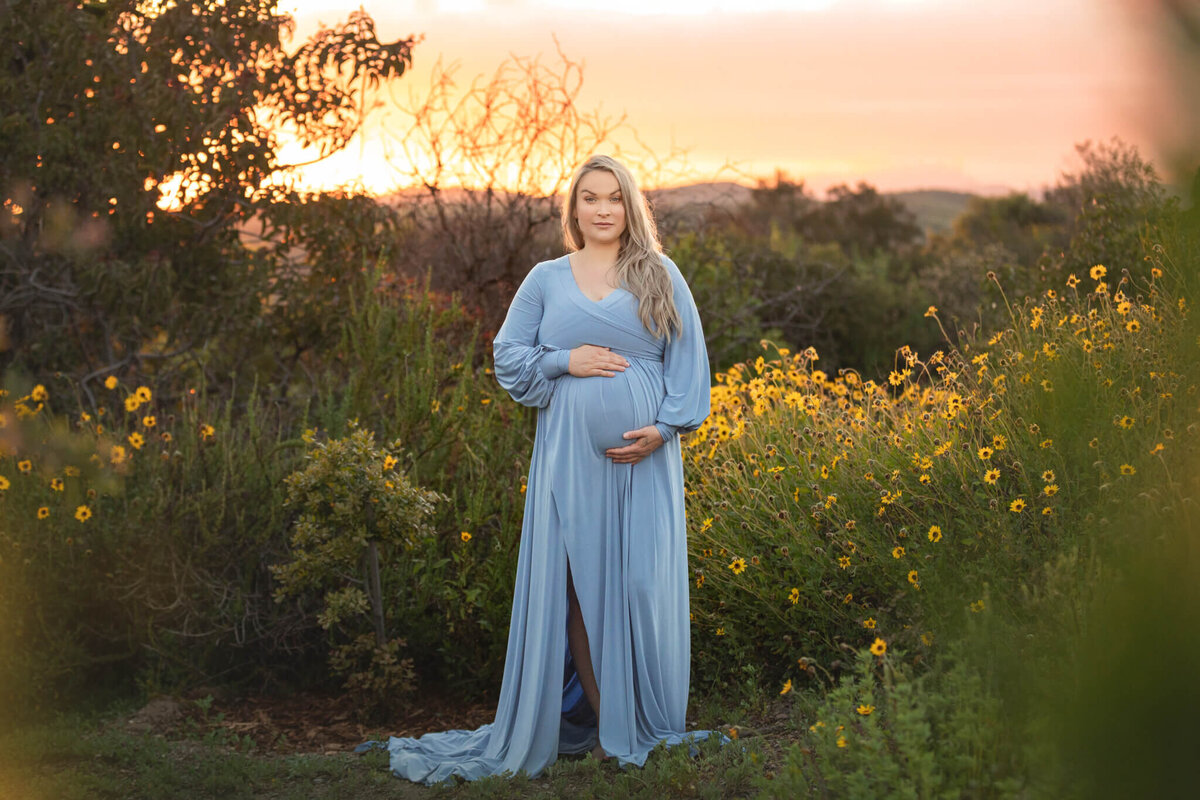 Mom to be in a blue maternity dress with sunset in the background photographed in Woodland Hills