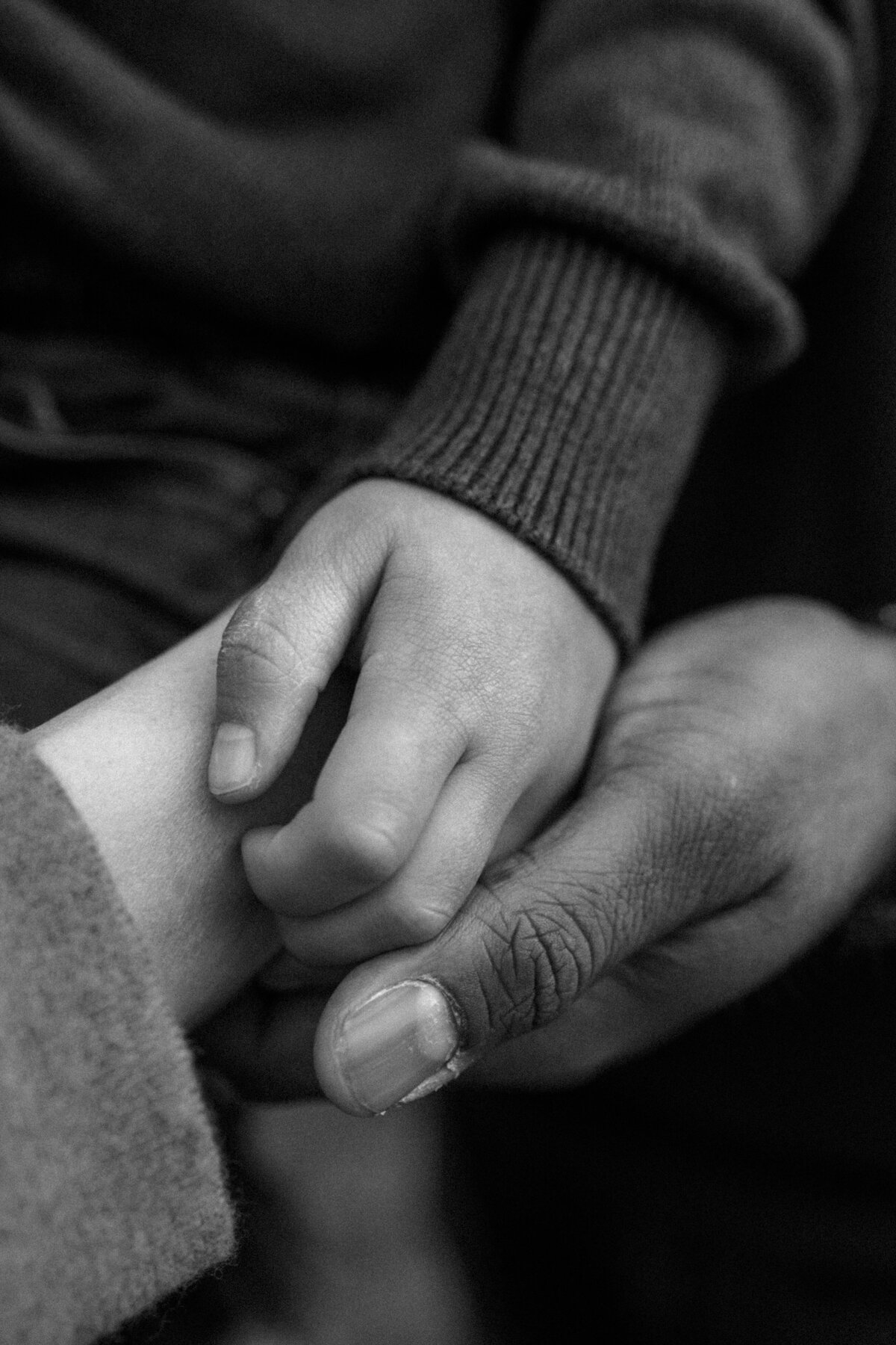 Close up detail of a young toddler's hands resting on his dad's larger hands.