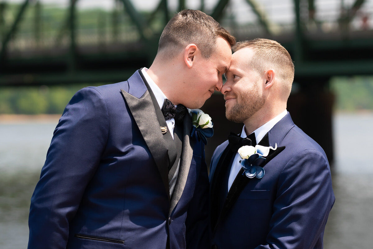 Grooms smile at each other on wedding day.