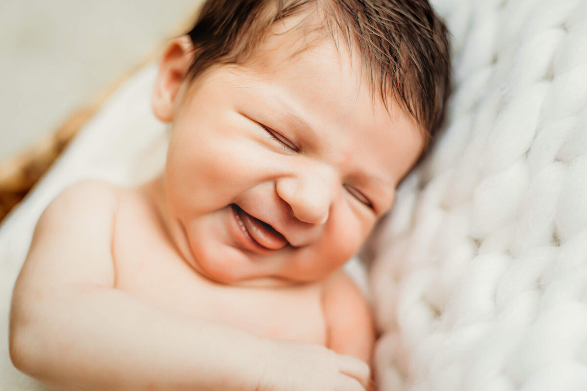 newborn girl smiling at camera while sleeping.