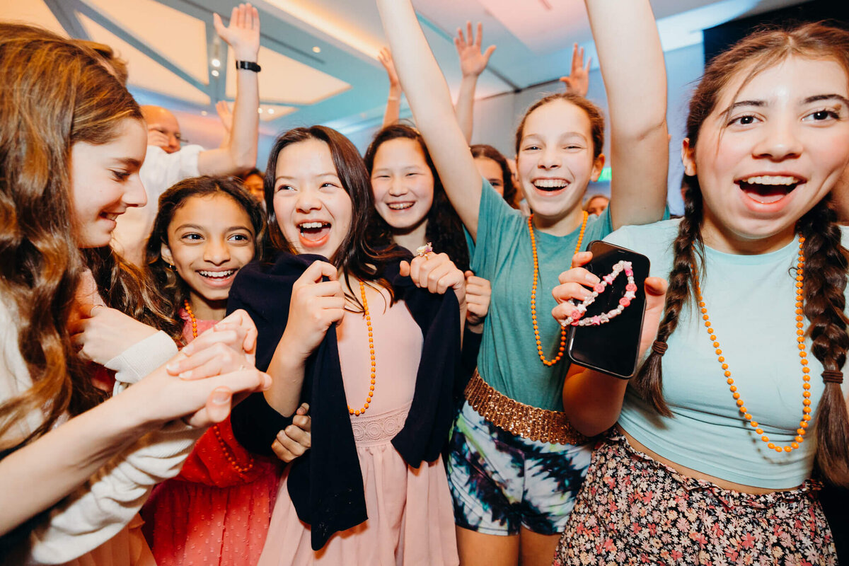 A bunch of teenage girls dance and celebrate with the party girl on the dance floor for some Bellevue Bar and Bat Mitzvah Photography