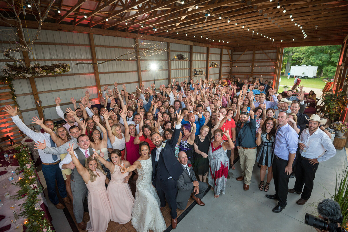 Wedding guests cheering while the DJ plays music at reception.