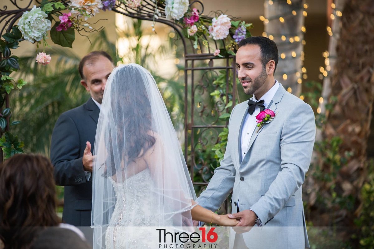 Officiant asks the Bride to repeat after him as she holds her Groom's hands at the altar