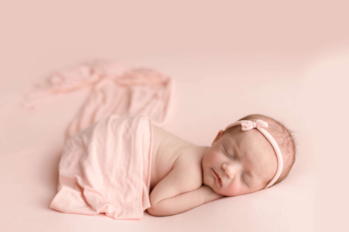 Baby girl sleeping on pink fabric