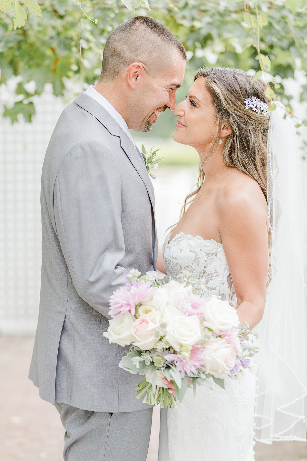 Bride and groom touch noses as they pose for a wedding portrait. Captured by best Massachusetts wedding photographer Lia Rose Weddings.