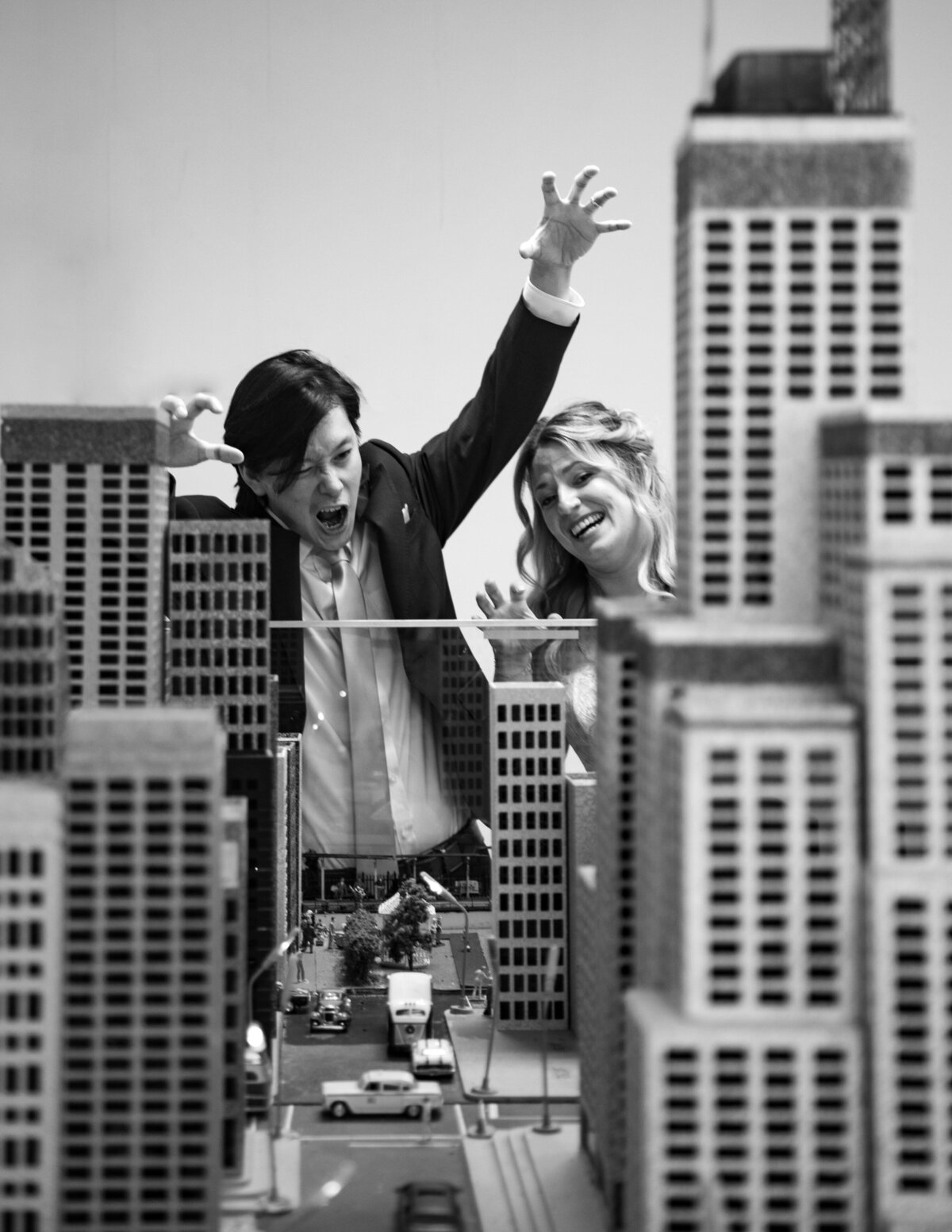 A black and white photo of a wedding couple towering over a city.
