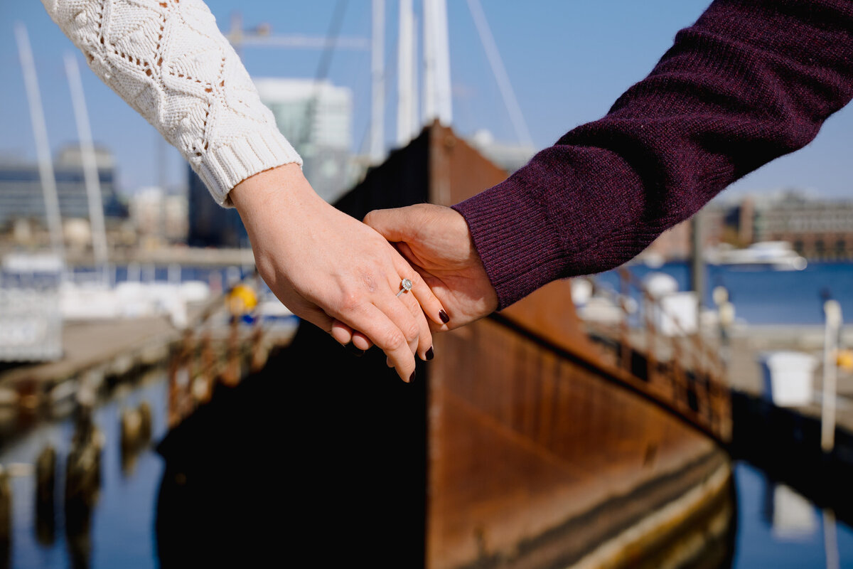 Two hands held together in front of a boat in the water.
