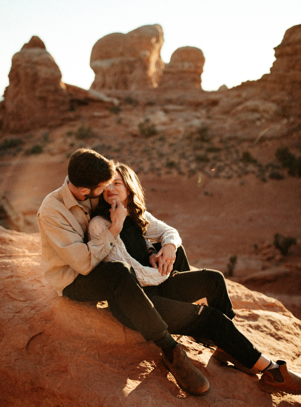 Couple sitting on a red rock in the desert